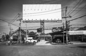 Schwarz-Weiß-Fotografie eines leeren Billboards nahe dem Flughafen Koh Samui, Thailand, umgeben von chaotischen Stromleitungen – Teil der Serie Billboards von J.F. Lindemann, Leica M und Summicron 28mm ASPH