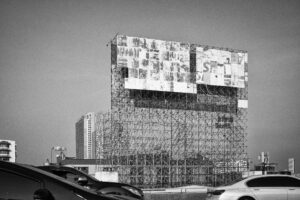 Schwarz-Weiß-Fotografie eines fragmentierten Billboards am Highway in Bangkok, Thailand – urbane Architektur und Autos im Vordergrund. Teil der Serie Billboards von J.F. Lindemann, Leica M, Summicron 28mm ASPH