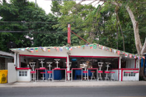 Geschlossene Bar mit hochgestellten roten Barhockern und bunten Fahnen in Koh Chang, Thailand – Fotografie aus der Serie FERMÉ-22 von J.F. Lindemann mit Leica M und Summicron 28mm ASPH