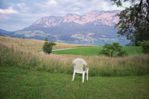 Weißer Monobloc-Plastikstuhl auf einer grünen Wiese mit Bergpanorama in Österreich · Fotografie von J.F. Lindemann · Leica M, 28mm Summicron