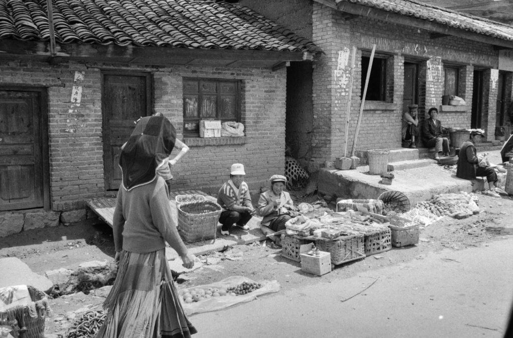 Marktszene mit Frauen vor traditionellen Häusern in Yunnan, China, 1993, Schwarzweiß-Fotografie mit Leica M6 und Summicron 35mm von J.F. Lindemann