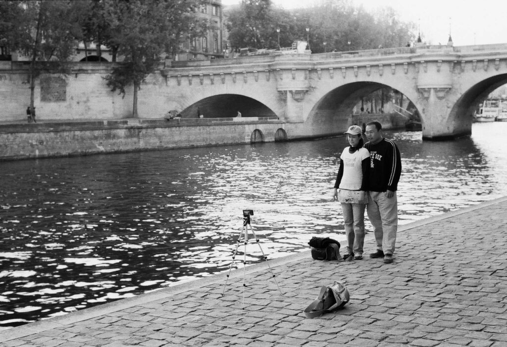 Touristenpaar macht ein Selfie am Seine-Ufer in Paris mit Stativ und Kamera, aufgenommen mit Leica M6 und Summicron 35mm f/2.0 ASPH von J.F. Lindemann