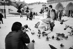 Hochzeitsfotograf in Paris fotografiert ein Brautpaar vor Notre-Dame, während Tauben auffliegen. Schwarzweißaufnahme von J.F. Lindemann mit Leica M und Summicron 28mm f/2.0 ASPH.