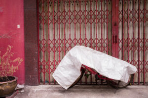 Motorrad unter weißer Plastikplane vor rotem Rolltor in urbaner Umgebung; Fotografie von J.F. Lindemann mit Leica M und Summicron 28mm f/2.0 ASPH, Serie WRAPPED