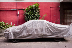 Mit Plastikplane abgedecktes Auto vor roter Wand mit Pflanzen; Farb-Fotografie mit Leica M und Summicron 35mm f/2.0 ASPH von J.F. Lindemann