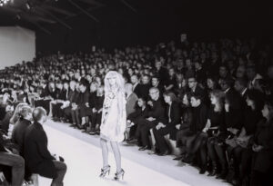 Model auf dem Laufsteg bei einer Haute Couture Show in Paris, umgeben von Publikum.