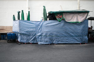 Blau-weiß gestreifte Plastikplane verdeckt Marktstand in Thailand – Fotografie aus der Serie FERMÉ-2 von J.F. Lindemann mit Leica M und Summicron 28mm ASPH