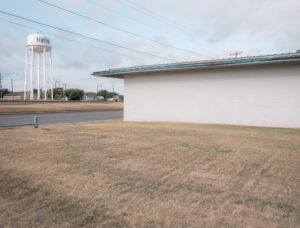 Niedriges Gebäude mit freier Fläche und Wasserturm im Hintergrund in Electra, Texas.