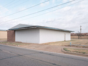 Flaches Gebäude an einer Straßenecke mit Stromleitungen in Electra, Texas.